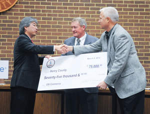 Virginia Secretary of Commerce and Trade Jim Cheng (left) shakes hands with Mike Bomba, vice president of fulfillment services for GSI, as they hold a check for $75,000 in grant funds to assist with the project. 